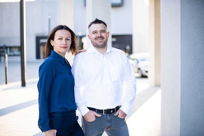 Teamfoto im Büro, Mitarbeiter stehen zusammen und lächeln in die Kamera, moderne Businessumgebung