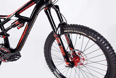 Robustes schwarz-rotes MTB mit Federgabel, seitlich aufgenommen, detailreiche Produktfotografie